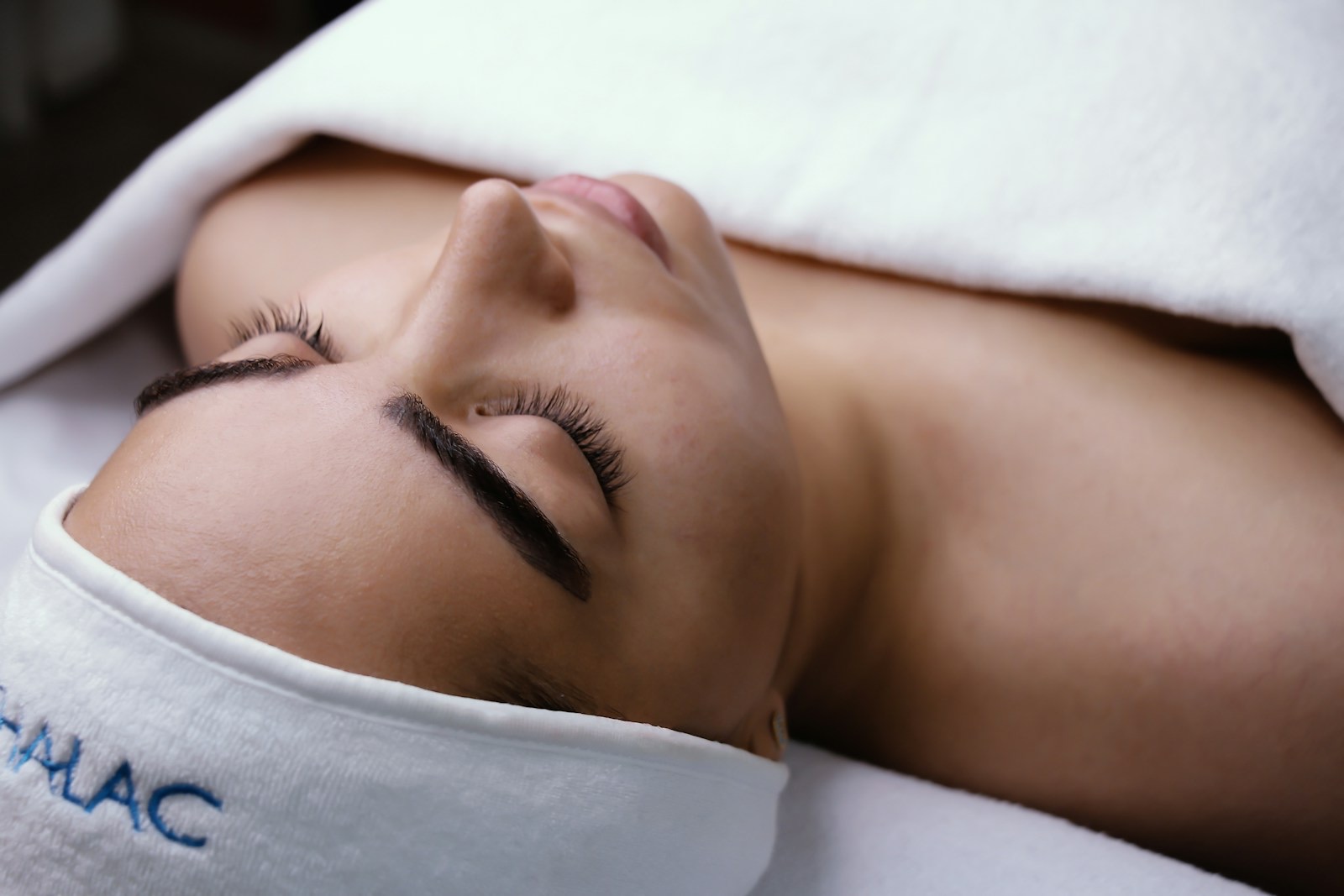 A person lying down, eyes closed, in deep relaxation, soft light and serenity.