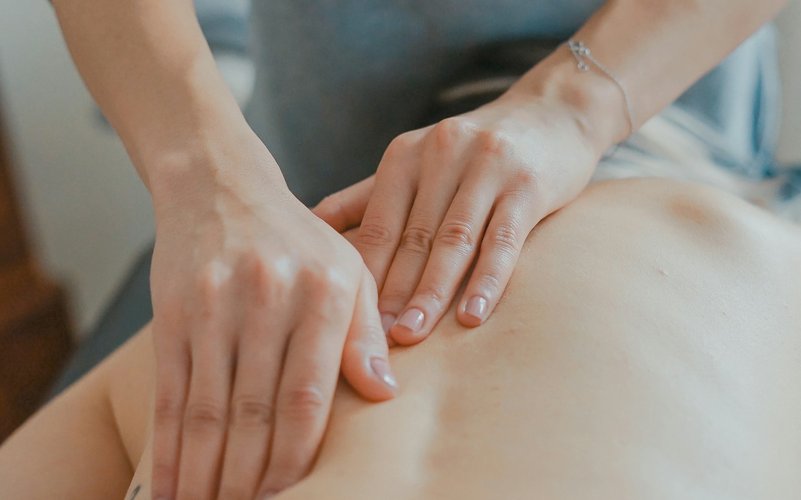 Massage therapist working a client's lower back, hands laid flat, soft natural light.